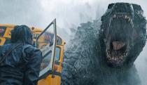 Godzilla roars at a person standing next to a school bus in Apple TV+ series Monarch: Legacy of Monsters.