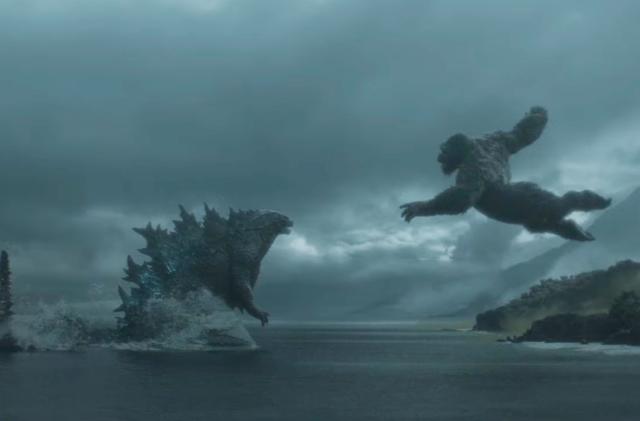 Godzilla and King Kong approach each other for battle: Godzilla wades through water as King Kong leaps at him from the coast.