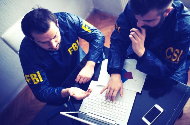 FBI and CSI agents working in the office on a crime. they are working on laptop   