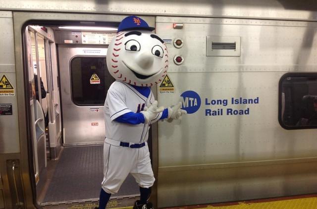 Mr. Met, the New York Mets mascot, stands in front of an MTA subway train.