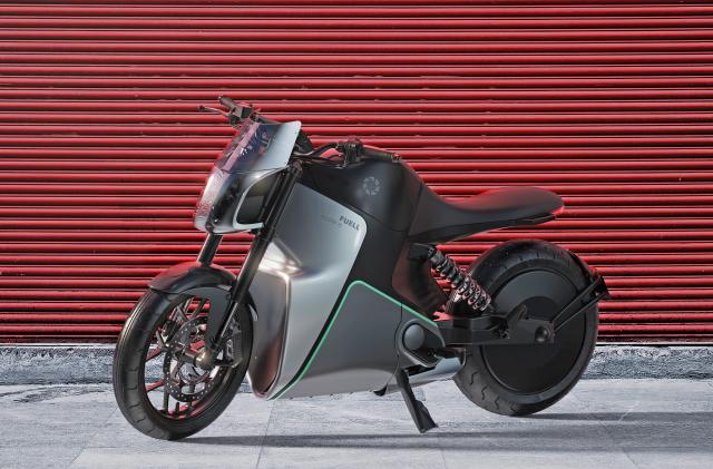 A press photo of Fuell Flloww electric motorcycle seen from the side on a sidewalk in front of a red roll down metal gate.