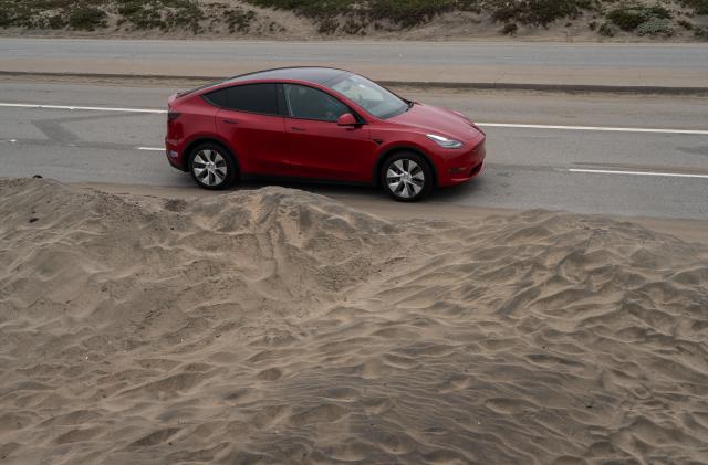 SAN FRANCISCO, CALIFORNIA - JUNE 26: A Tesla drives along a section of the Upper Great Highway where sand encroaches on the road from Ocean Beach on June 26, 2023 in San Francisco, California. A recent U.S. Geological Survey study concludes that "by 2100, the model estimates that 25-70 percent of California's beaches may become completely eroded due to sea level rise scenarios of .5 to 3.0 meters, respectively."  (Photo by Loren Elliott/Getty Images)