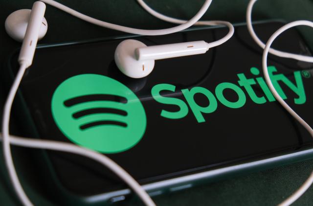 Spotify logo displayed on a phone screen and headphones are seen in this illustration photo taken in Krakow, Poland on February 3, 2022. (Photo Illustration by Jakub Porzycki/NurPhoto via Getty Images)