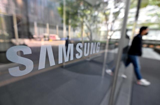 A man walks past the Samsung logo displayed on a glass door at the company's Seocho building in Seoul on April 7, 2023. - Samsung Electronics said on April 7 it expected first-quarter operating profits to plunge over 95 percent on-year to a 14-year low, as memory chip sales were hammered by a global downturn. (Photo by Jung Yeon-je / AFP) (Photo by JUNG YEON-JE/AFP via Getty Images)
