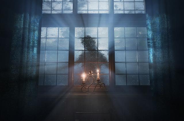 A silouetted lady stands behind a spooky candle-lit window pane in this promotional image from the game Layers of Fear.