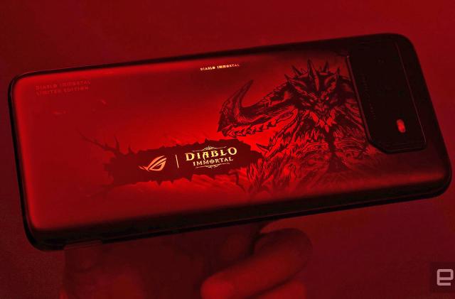 The ROG Phone 6 Diablo Immortal Edition seen resting on someone's hand in very dark red light.